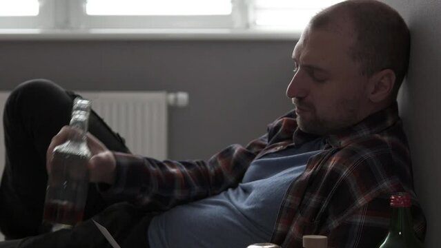 Depressed man drinks alcohol and looks at a photo of his wonderful life. Alcohol addiction concept.