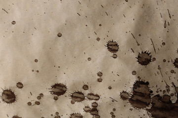 Black brown Ink watercolor spray blot on beige grain texture paper background.