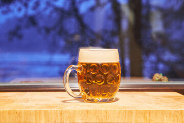 Mug of famous czech pilsner lager beer in front of window during the cold winter evening. Special...