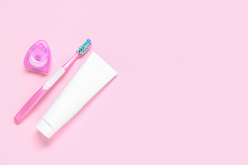 Toothbrush with toothpaste and dental floss on color background.