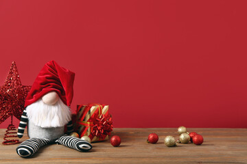 Christmas gnome with gift boxes and decorations on red background