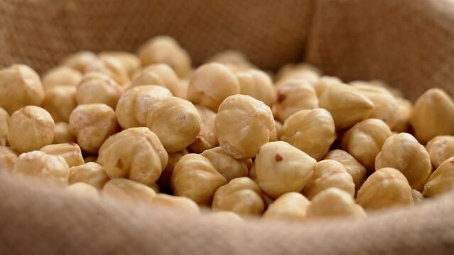 Peeled hazelnut kernels on a rough burlap cloth. Shelled filbert nuts. Rotation
