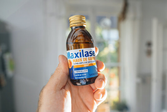 Frankfurt, Germany - Jun 12, 2023: Male hand holding Maxilase alpha-amylase 200 units by Sanofi laboratory