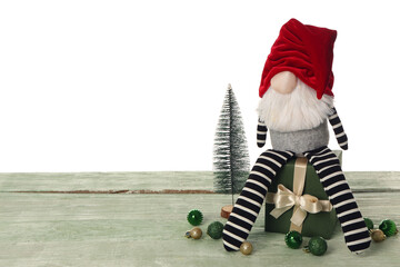 Christmas gnome with gift box, balls and decorative fir on green wooden table against white...