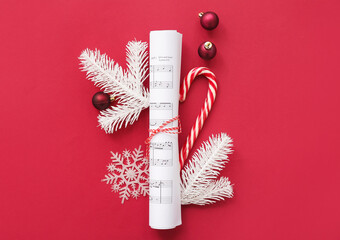 Rolled music note sheets with Christmas decor on red background