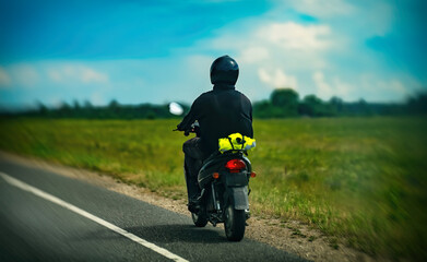 Obraz premium Man rides a motorcycle on the road. Back view.
