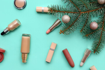 Different decorative cosmetics with Christmas tree branches and balls on turquoise background