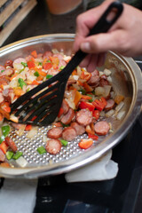 preparing food in the kitchen,Close-up of the texture of the ingredients. Vegetables with vivid colors. preparation of a dish with vegetables, ingredients for Stew with peppers and sausage, hand stirs