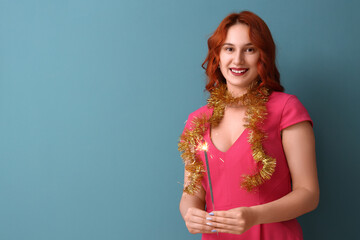 Smiling woman with sparklers celebrating Christmas on blue background