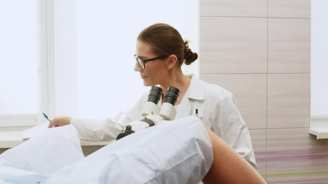 Female Gynecologist examining patient on chair with gynecological equipment. Colposcopy, examination of a cervical cancer. Colposcope close-up. Maternity fertility IVF issues. Abortion and ovulation