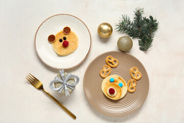 Plates with pancakes in shape of reindeer and bear on white table. Christmas celebration