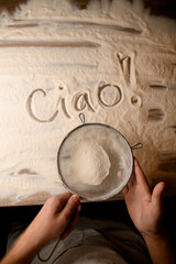 Ciao inscription on flour and flour mesh. Culinary greetings.