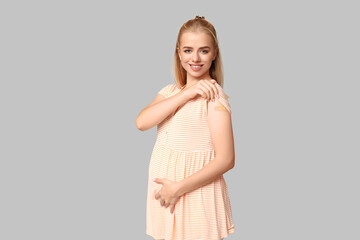 Beautiful young pregnant woman with applied medical patch on grey background