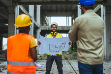 Group of engineers with blueprints standing on construction site. Architecture engineering at workplace. Architects and engineers are very pleased with the progress on the construction site
