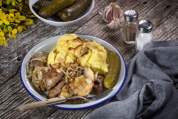 Fried liver with onion and apple, served with boiled potatoes and pickled cucumber.