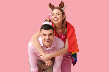 Obraz premium Young couple with LGBT flag on pink background