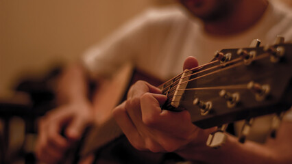 Close up of a man playing acoustic guitar, shallow depth of field