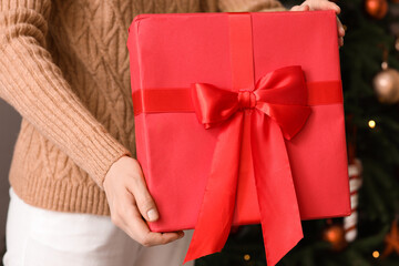 Young woman with Christmas gift box at home, closeup