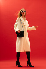 Fashionable confident woman wearing trendy white boucle midi coat, stylish sunglasses, over the...