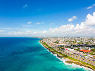 Aerial view of Santo Domingo este. The Autopista Las Americas along the rocky shore of turquoise caribbean sea. Expressway from the Punta Cana to the capital of Dominican Republic - obrazy, fototapety, plakaty