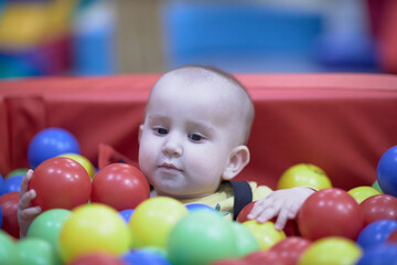 Fototapeta na wymiar a one-year-old child, a boy, a joyful kid in toys, a lot of balls