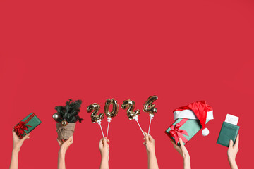 Female hands holding figure 2024 with passport and gifts on red background. New year vacation concept