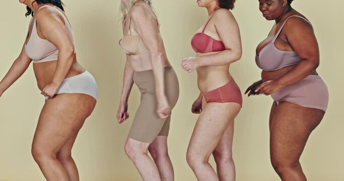 Dancing, body positivity and closeup of women in underwear in a studio for self love celebration. Diversity, freedom and female people moving to music with confidence together by green background.