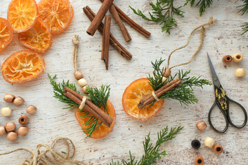 Making natural Christmas tree winter holiday ornaments - dried orange slices, cinnamon sticks and greenery
