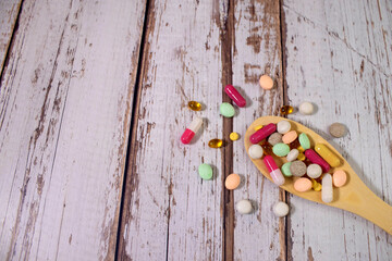 Assorted pharmaceutical medicine pills, tablets and capsules on wooden spoon