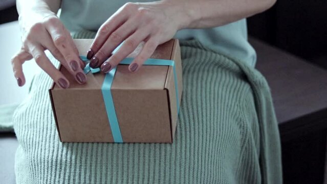 Close up slow motion footage of the woman unwrapping the gift. Concept