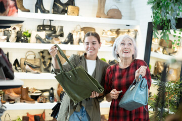 Two cheerful female shoppers, young girl and elderly woman, admiring and enthusiastically...