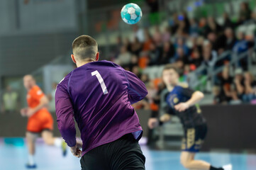 handball goalkeeper throw ball to other player during handball match.