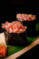 Big sushi with salmon, black nori and ginger on a dark background