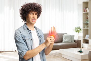 Young man in a living room holding his painful inflamed palm