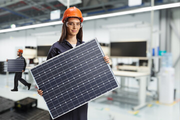 Solar panel production line, female worker in a factory holding a photovoltaic panel