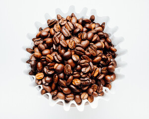 dark roast coffee beans in a paper coffee filter viewed from above on white background