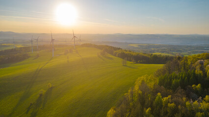 Naklejka na ściany i meble Wind power plant at sunset time. Clean and sustainable energy theme. Aerial drone view.