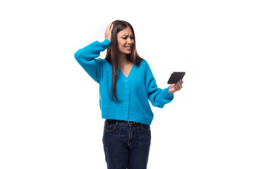 Fototapeta premium charming caucasian woman with black hair dressed in a blue cardigan watches attentively the video on the smartphone. e-business concept