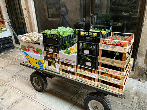 Venice, Italy - September 16, 2023: The hand drawn wagon of a grocer is loaded with crates of fruit and vegetables. A necessary tool for a business in a pedestrian city with no cars or trucks.
