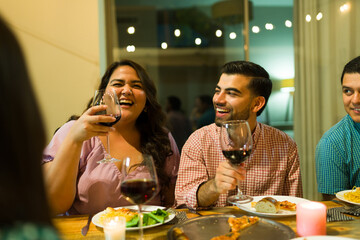 Happy friends smiling drinking wine at dinner