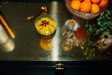 Sholeh Zard, a Persian saffron rice pudding, dessert with pomegranate and cinnamon garnish on metallic gold table