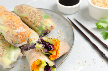 Vegetarian vietnamese spring rolls with carrot, cucumber, red cabbage, cilantro, sesame and rice noodle on a gray plate. veggie dish. Vegan food. Horizontal orientation. Selective focus