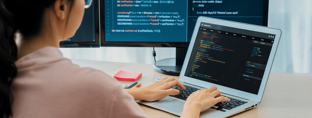 Cropped image of female web developer coding on laptop while computer displayed program and...