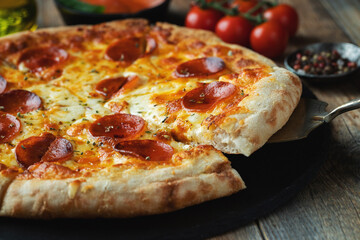 A slice of hot Italian pizza with stretching cheese. Pizza pepperoni on a dark wooden background