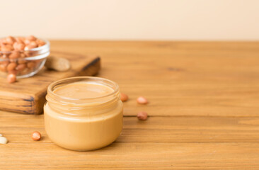 Fototapeta na wymiar Jar of peanut butter on wooden table