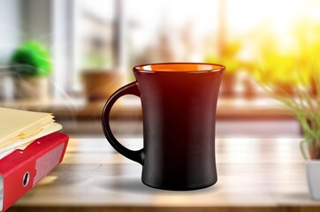 coffee cup on desk, note book by window