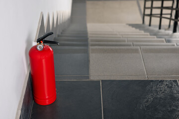 Red fire extinguisher near white wall, space for text