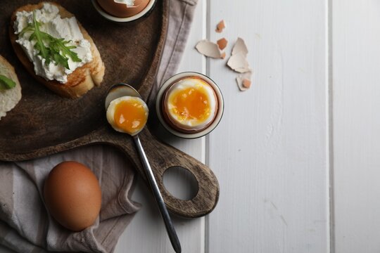 Breakfast with soft boiled egg served on white wooden table, flat lay. Space for text