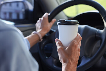 Coffee to go. Woman with paper cup of drink driving her car, closeup
