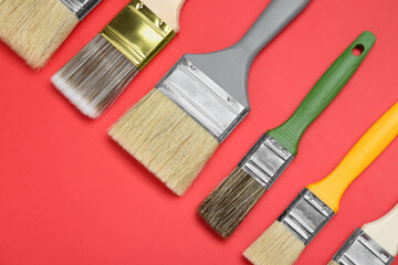 Many different paint brushes on red background, flat lay